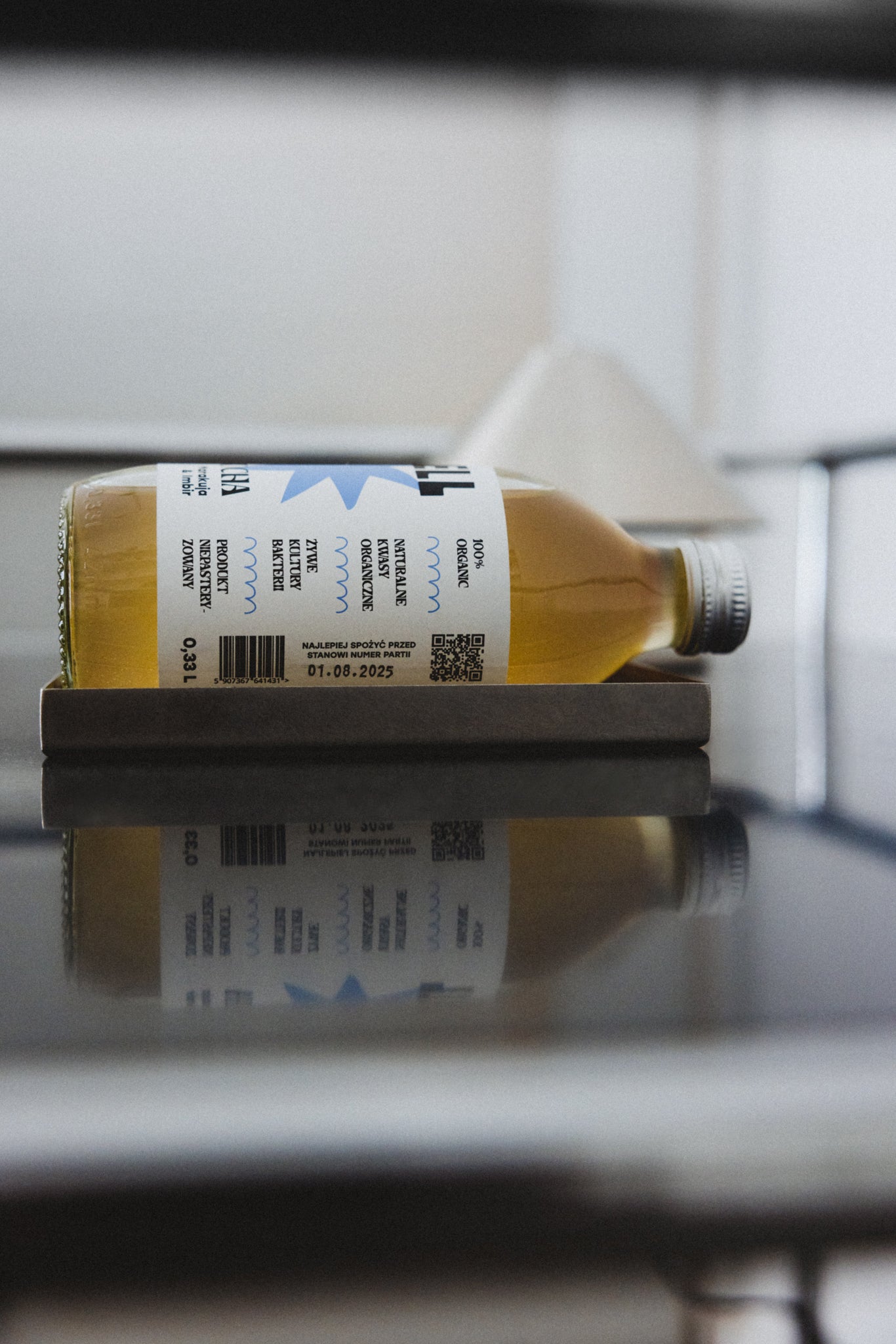 Kombucha na metalowej tacce, z etykietą przedstawiającą jej właściwości